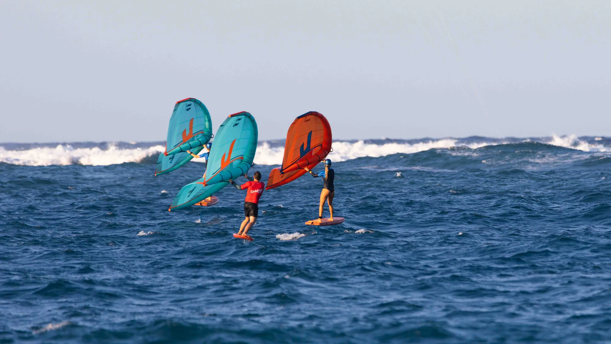 Three wingfoilers flying above the water off Cabarete