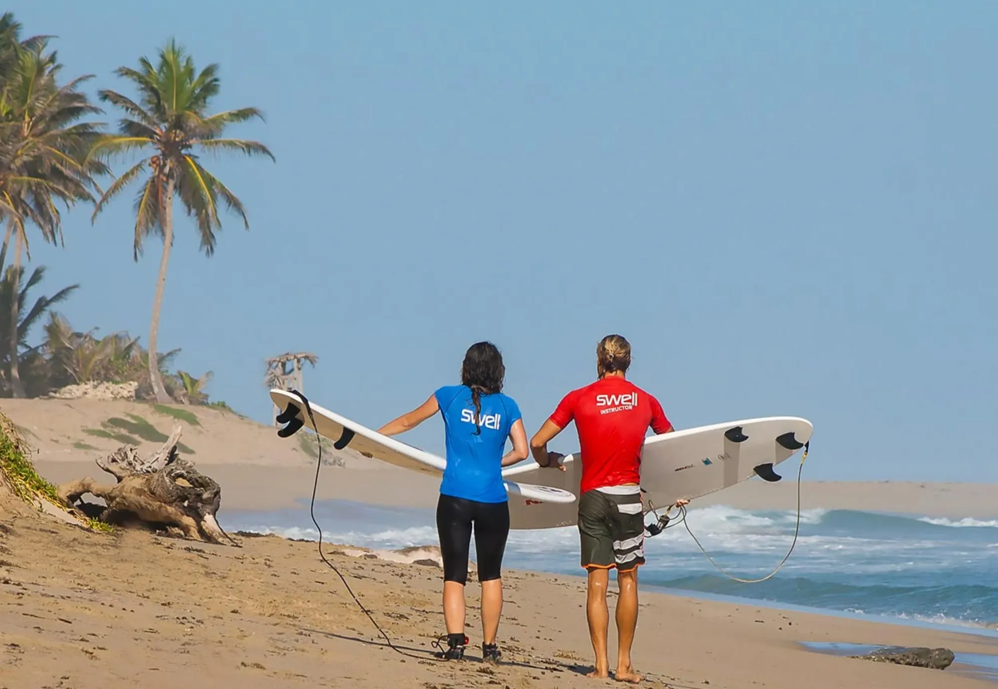 A Swell coach and guest heading to the water together