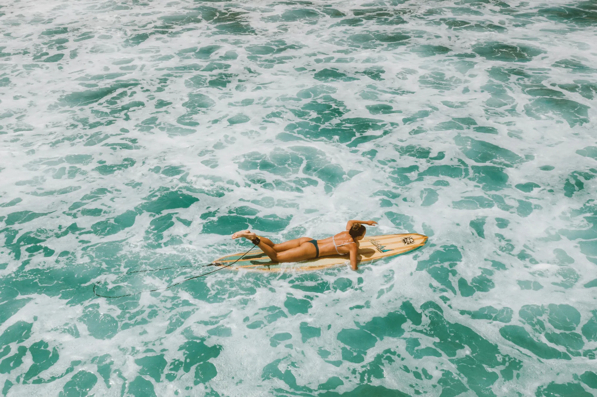 A surfer paddling out into clean Caribbean water